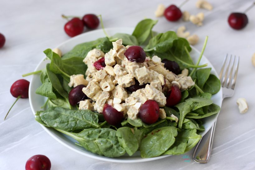 Vegan Cherry Cashew Chicken Salad on top of baby spinach