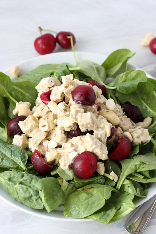 Vegan Cherry Cashew Chicken Salad on top of baby spinach