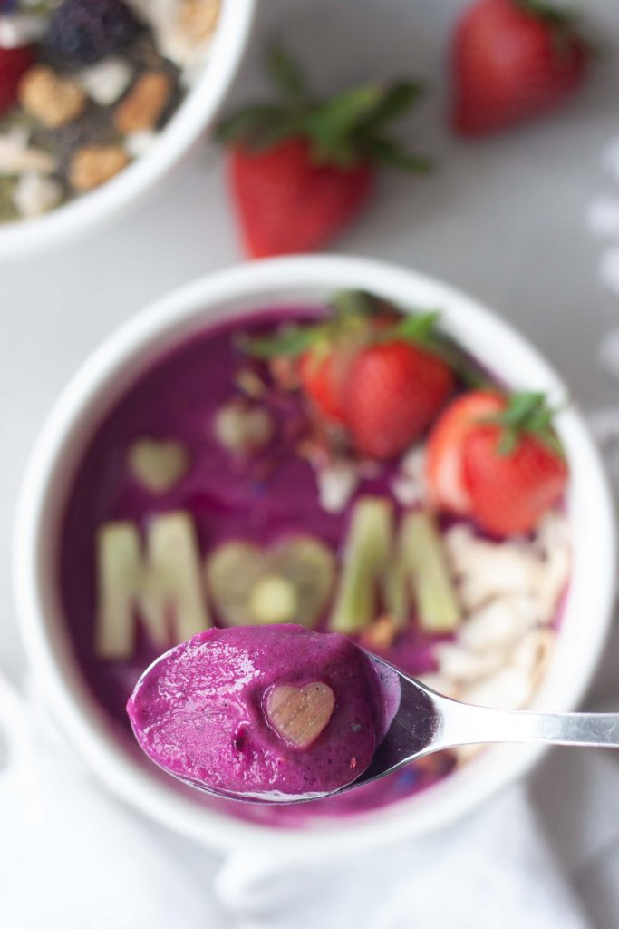 Supermom (with pink power) Superfood Smoothie Bowl made with love just for mom. Spoon with smoothie and heart.