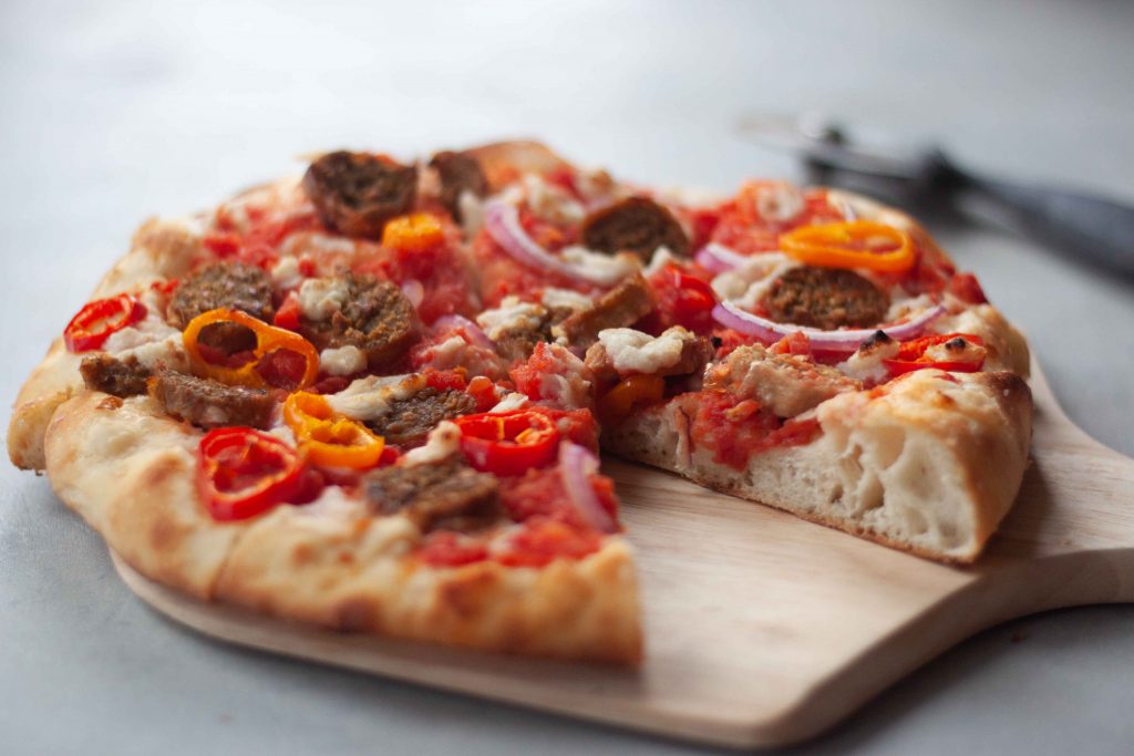 sliced sausage pizza on wood board