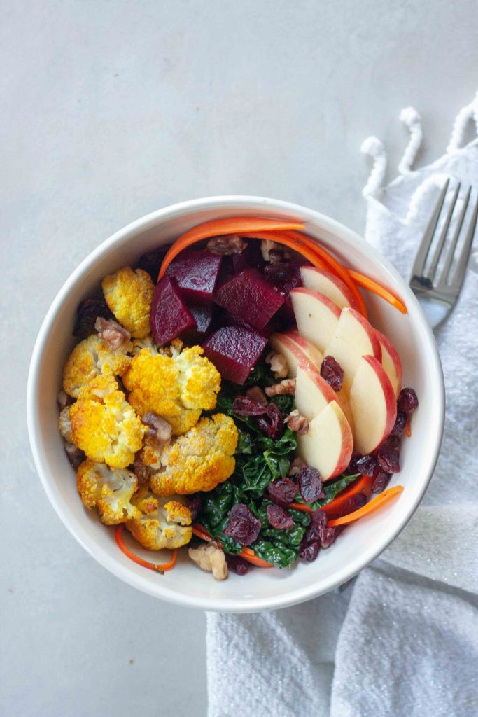 Buddha Bowl packed with anti- inflammatory whole foods, kale, beets, turmeric cauliflower, cranberries, apples, carrots, and walnuts.