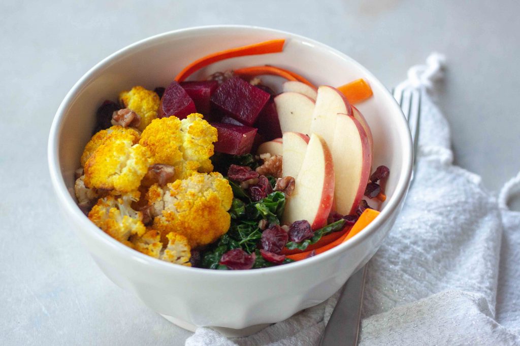 Buddha Bowl packed with anti- inflammatory whole foods, kale, beets, turmeric cauliflower, cranberries, apples, carrots, and walnuts.