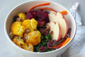 Buddha Bowl packed with anti- inflammatory whole foods, kale, beets, turmeric cauliflower, cranberries, apples, carrots, and walnuts.