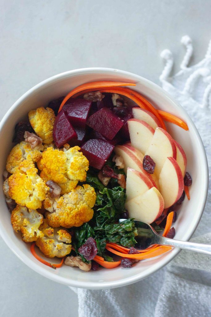 Buddha Bowl packed with anti- inflammatory whole foods, kale, beets, turmeric cauliflower, cranberries, apples, carrots, and walnuts.