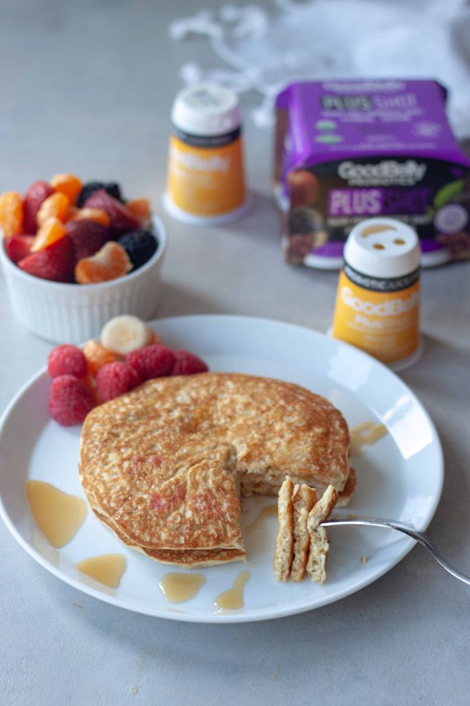 Inside of Oatmeal Pancakes topped with syrup, side of fruit and GoodBelly Probiotics.