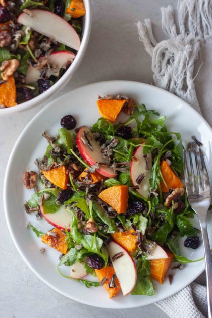 Plate of Wild Rice Roasted Butternut Squash Salad with fork, bowl in background.