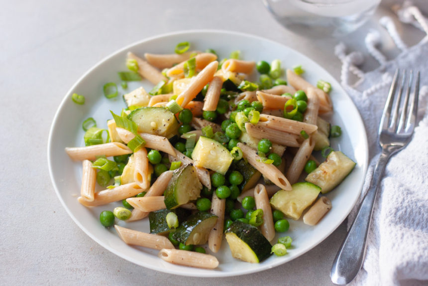 Plate with pasta, zucchini, peas, and a fork