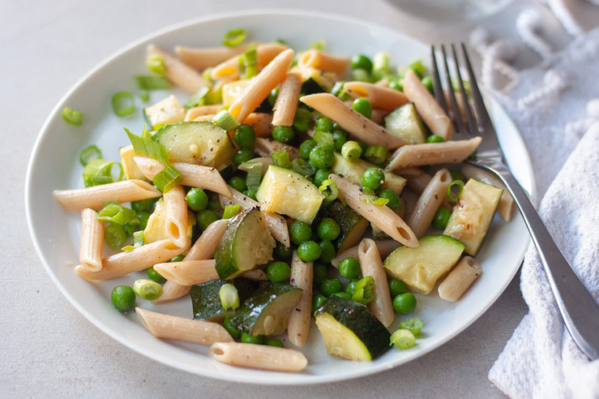 Plate with pasta, zucchini, peas, and a fork