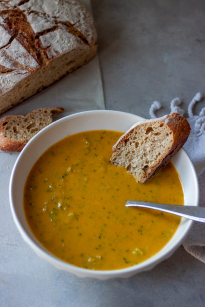 Bowl of Cheesy Broccoli No Cheese Soup with spoon and bread