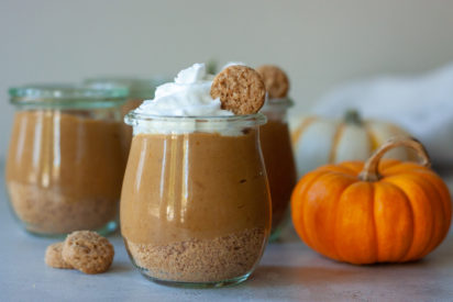 Jars with pumpkin pudding, whip cream, mini cookie, and pumpkins